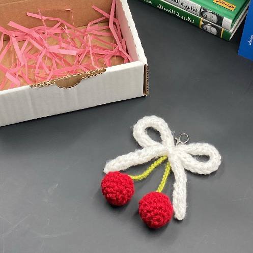 ميدالية مفاتيح كروشيه – تصميم حبات الكرز وربطة الفيونكة البيضاء